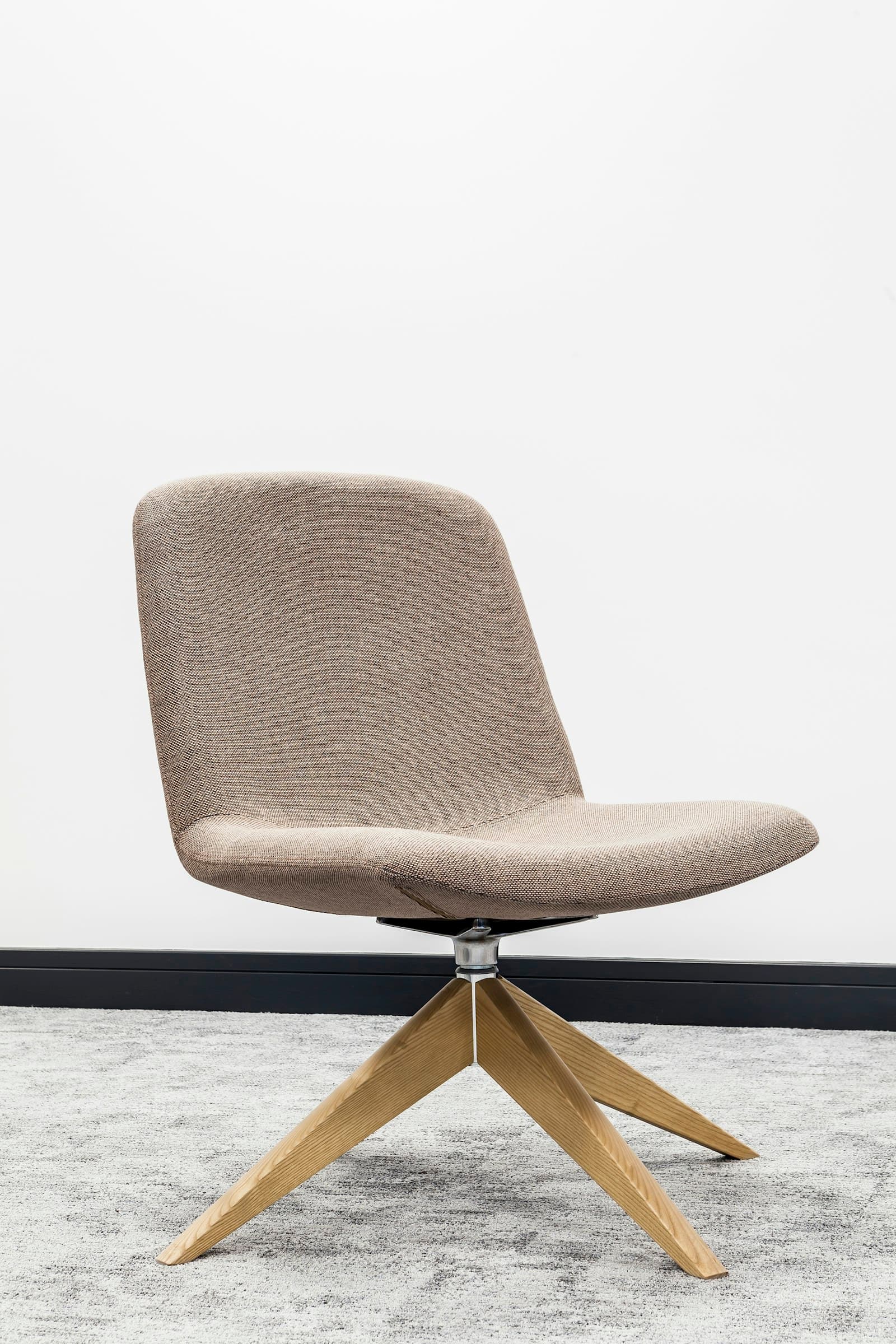 Beige upholstered swivel chair with a light oak star base on a grey rug