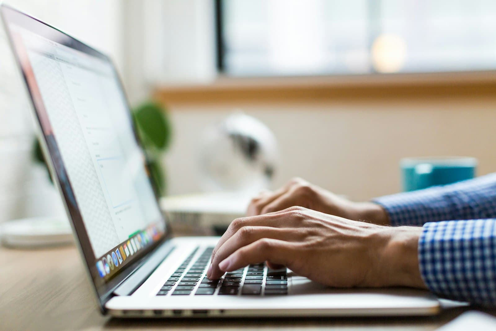 Hands typing on a laptop at a wooden desk