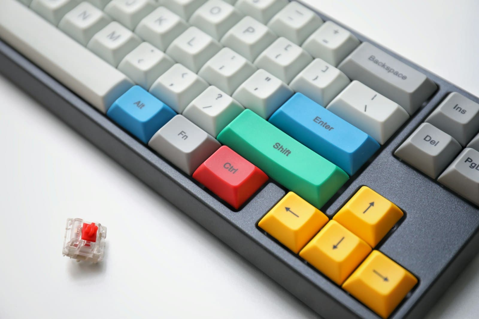 Close-up of a mechanical keyboard with colorful modifier keys and a loose switch beside it