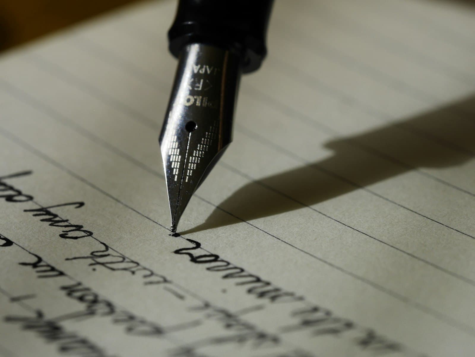 Fountain pen nib writing a line on cream paper