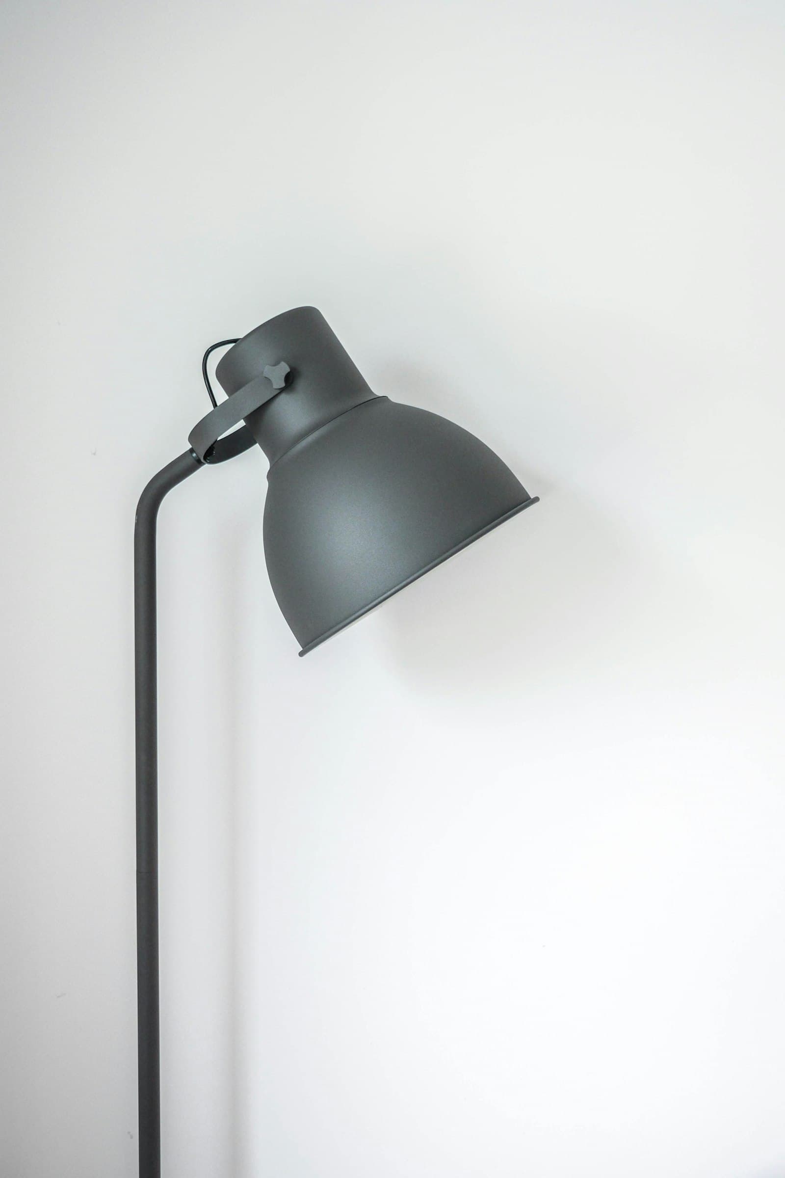 Matte grey floor lamp with an adjustable dome shade against a white wall